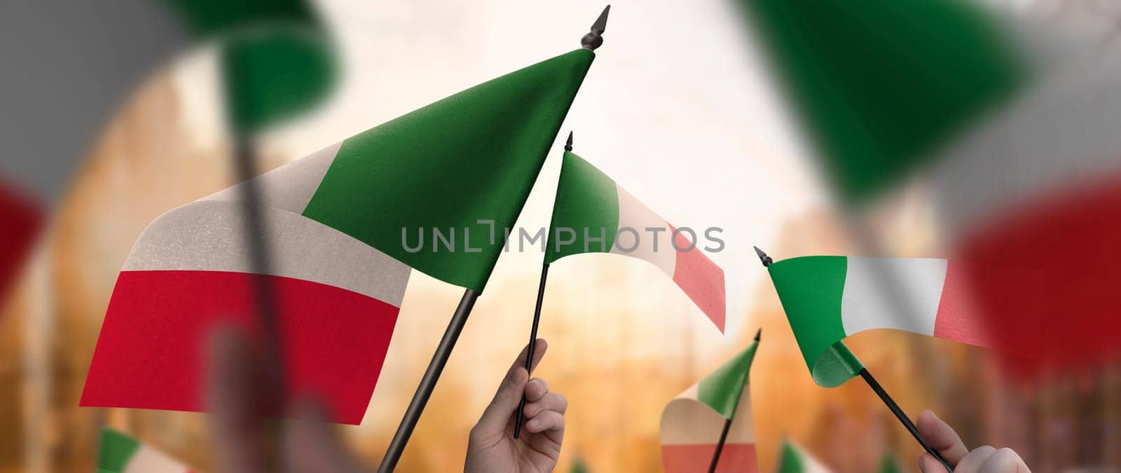Italy flags in their hands on a blurred urban background. The photo illustration was created without the use of artificial intelligence, only using Photoshop.