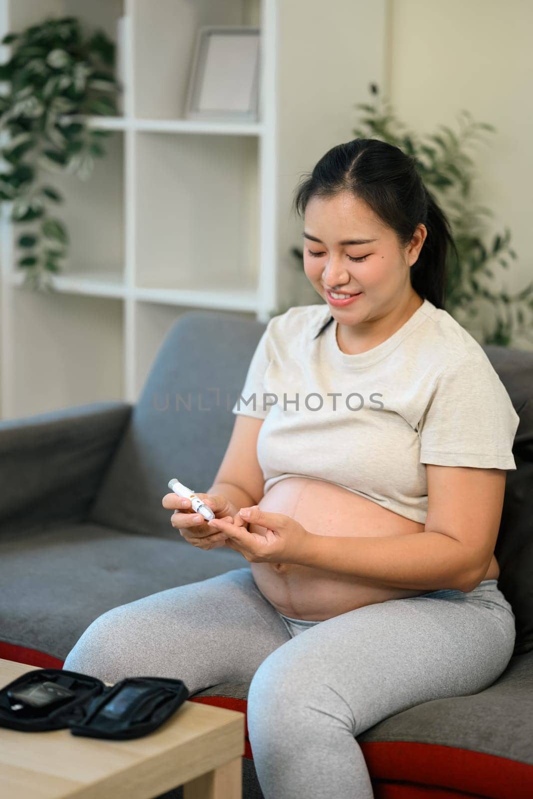 Pregnant woman monitoring her glucose levels with a finger prick test.