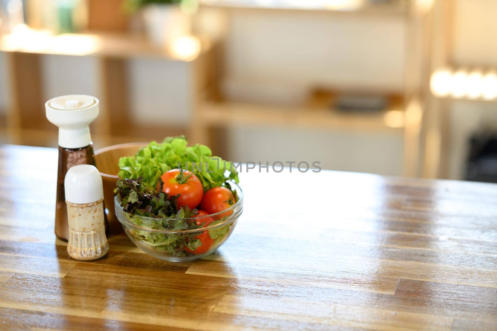 Fresh salad ingredients and seasoning bottles on a wooden kitchen counter in natural light.