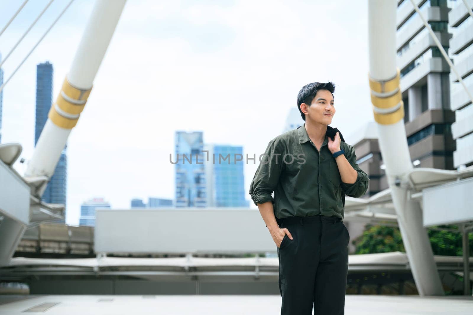 Confident young businessman walking outdoors with a jacket over his shoulder.