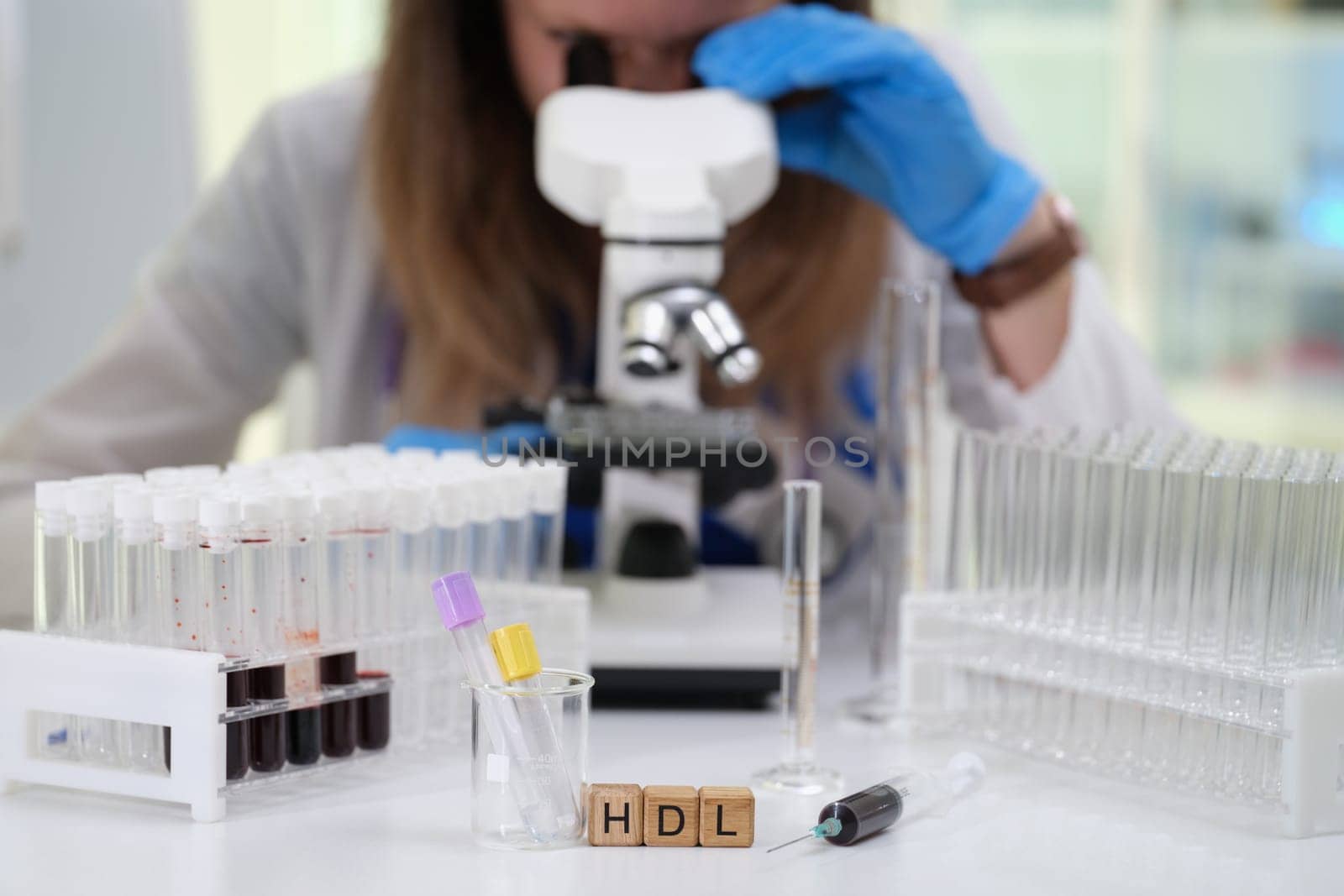 A researcher observes biological samples under a microscope, focusing specifically on HDL cholesterol levels