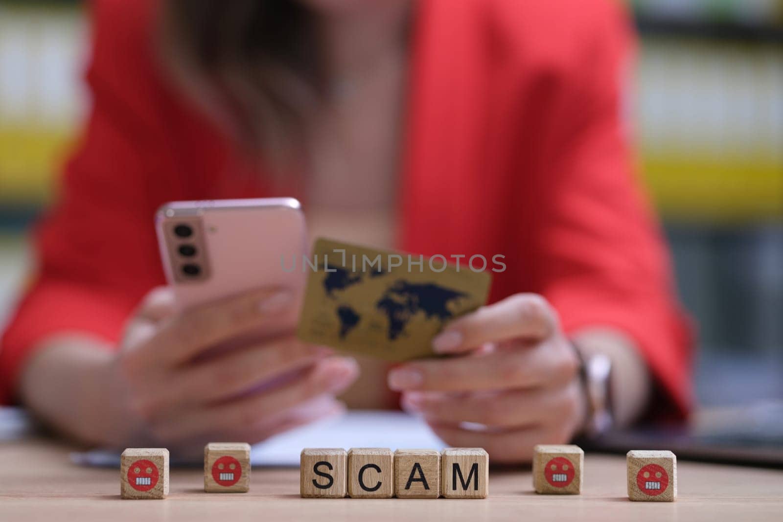 A woman is holding a phone and a credit card, underscoring the importance of being aware of digital scams