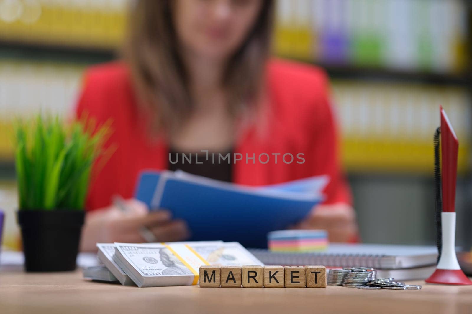 A focused woman meticulously reviews important reports in a vibrant and energetic office, symbolizing market analysis