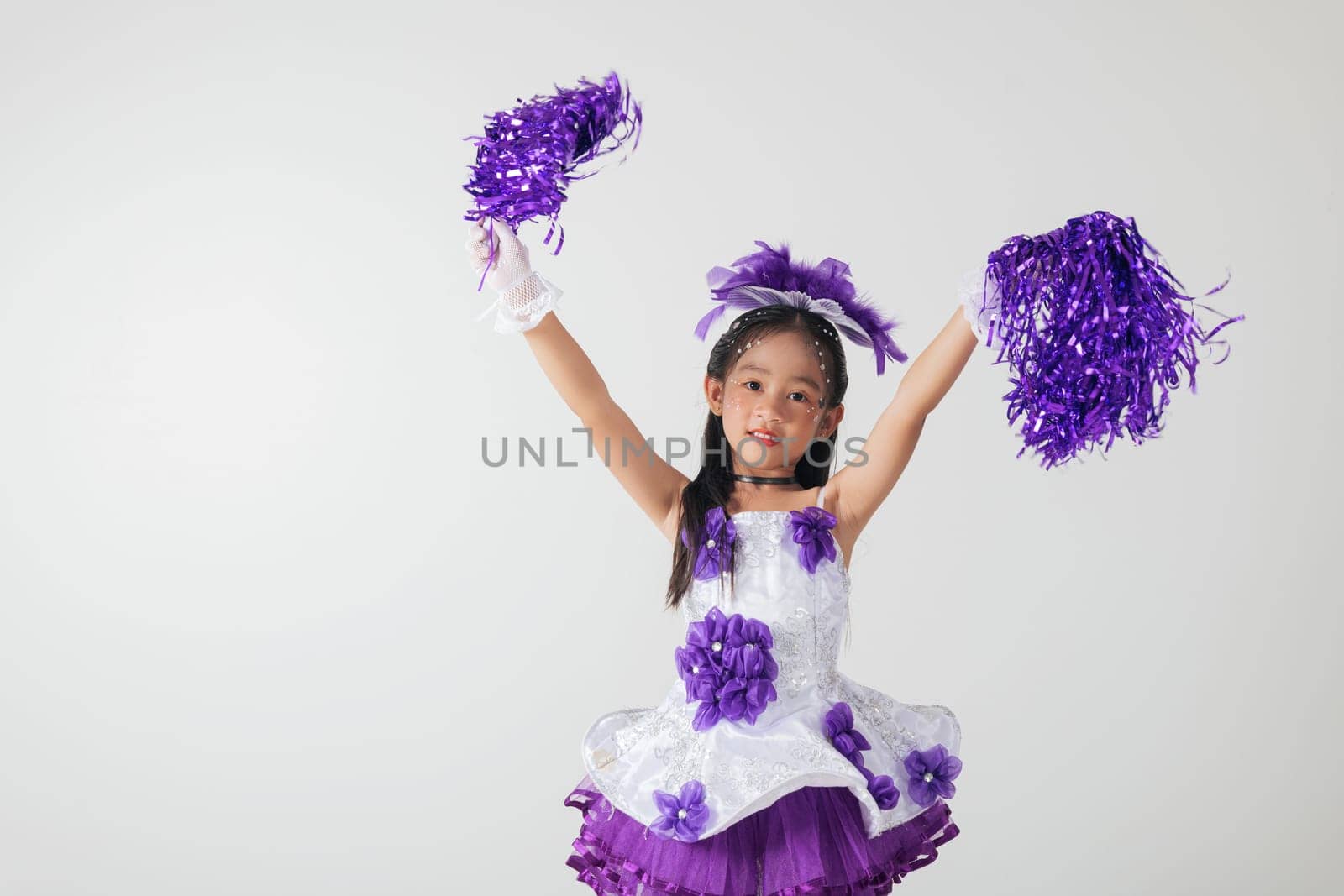 Adorable kid in cheerleading outfit with purple pom-poms. Studio photo on white, showcasing her happiness and energetic cheer. cheerleader kid