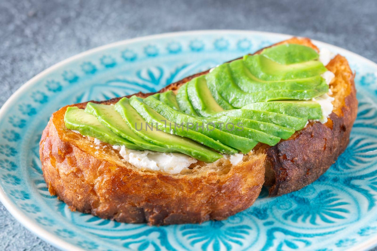 Bright avocado rests on creamy labneh, textures contrast beautifully on toasted bread