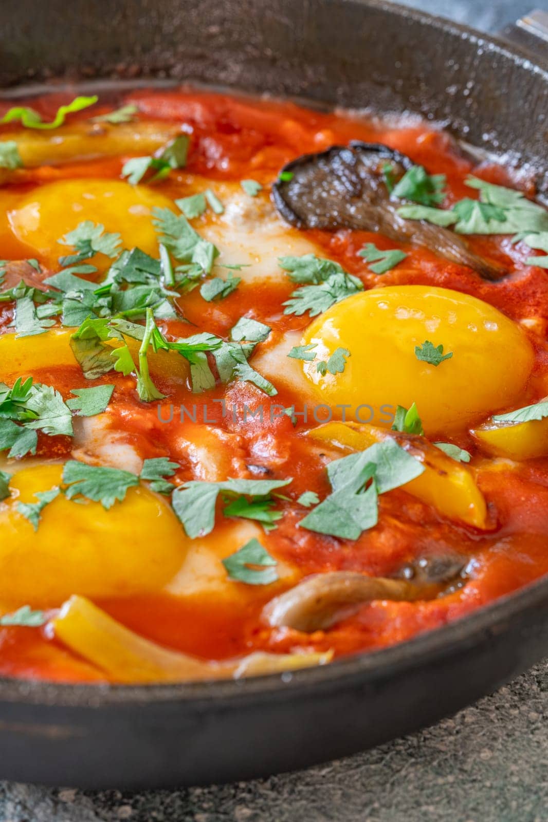 Eggs simmered in spiced tomato base with mushrooms, peppers, and fresh herbs