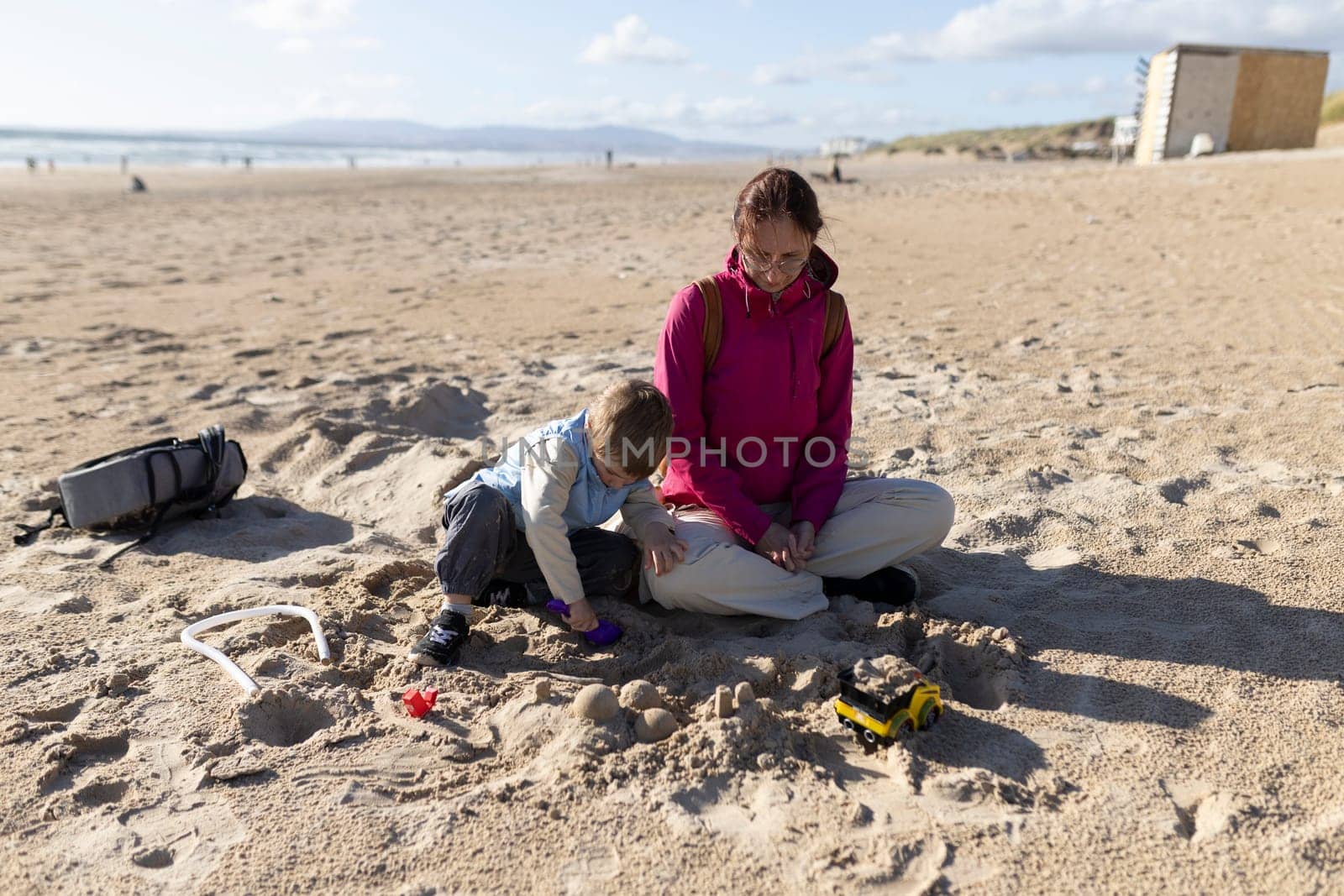 Mother and son enjoying quality time together, building sandcastles on a sunny beach