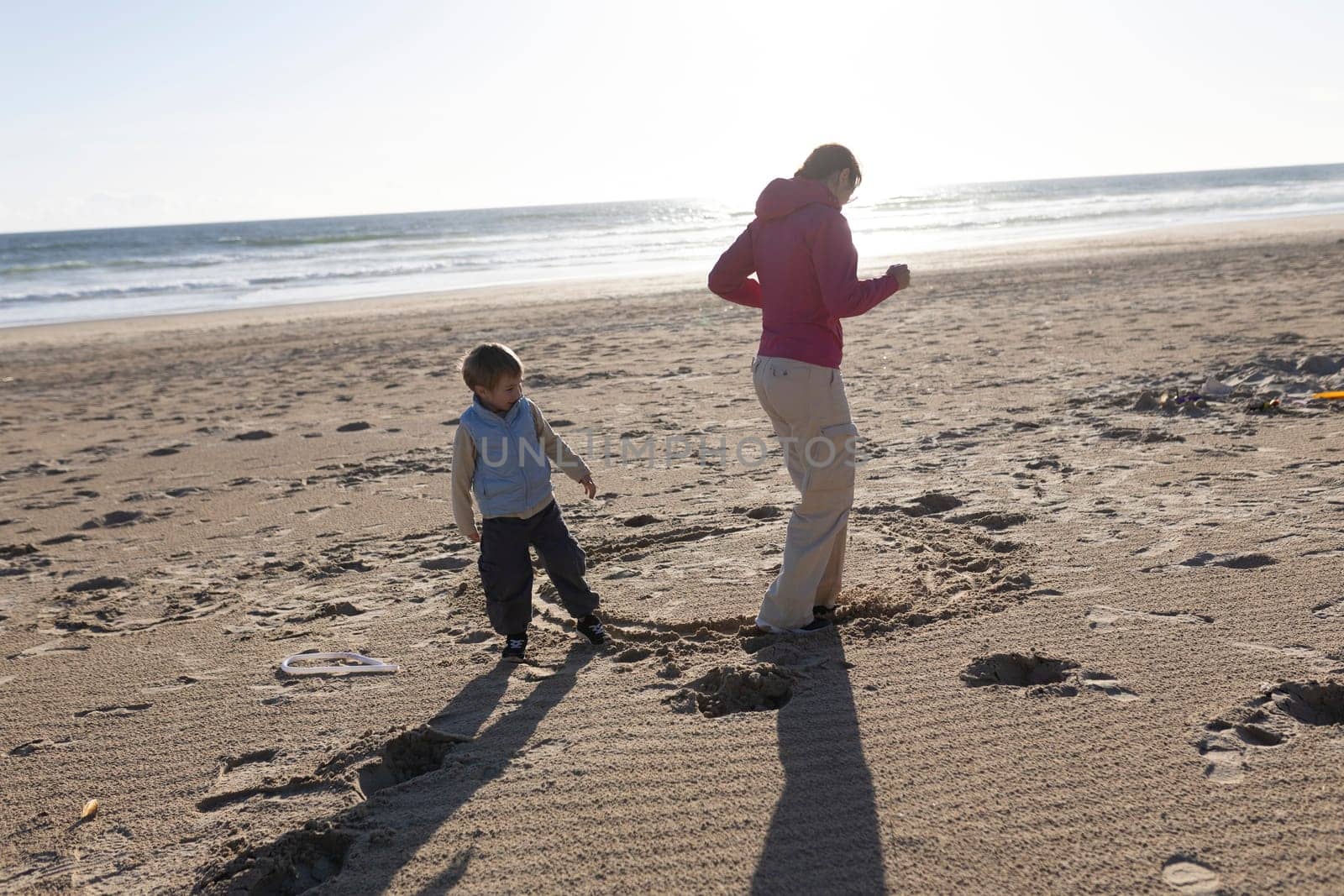 Mother and son enjoying a playful moment on the beach at sunset