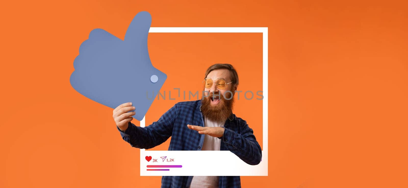 A man with a beard and glasses celebrates his success by making a thumbs up gesture while engaging with his online audience. The bright orange background enhances his joyful expression.