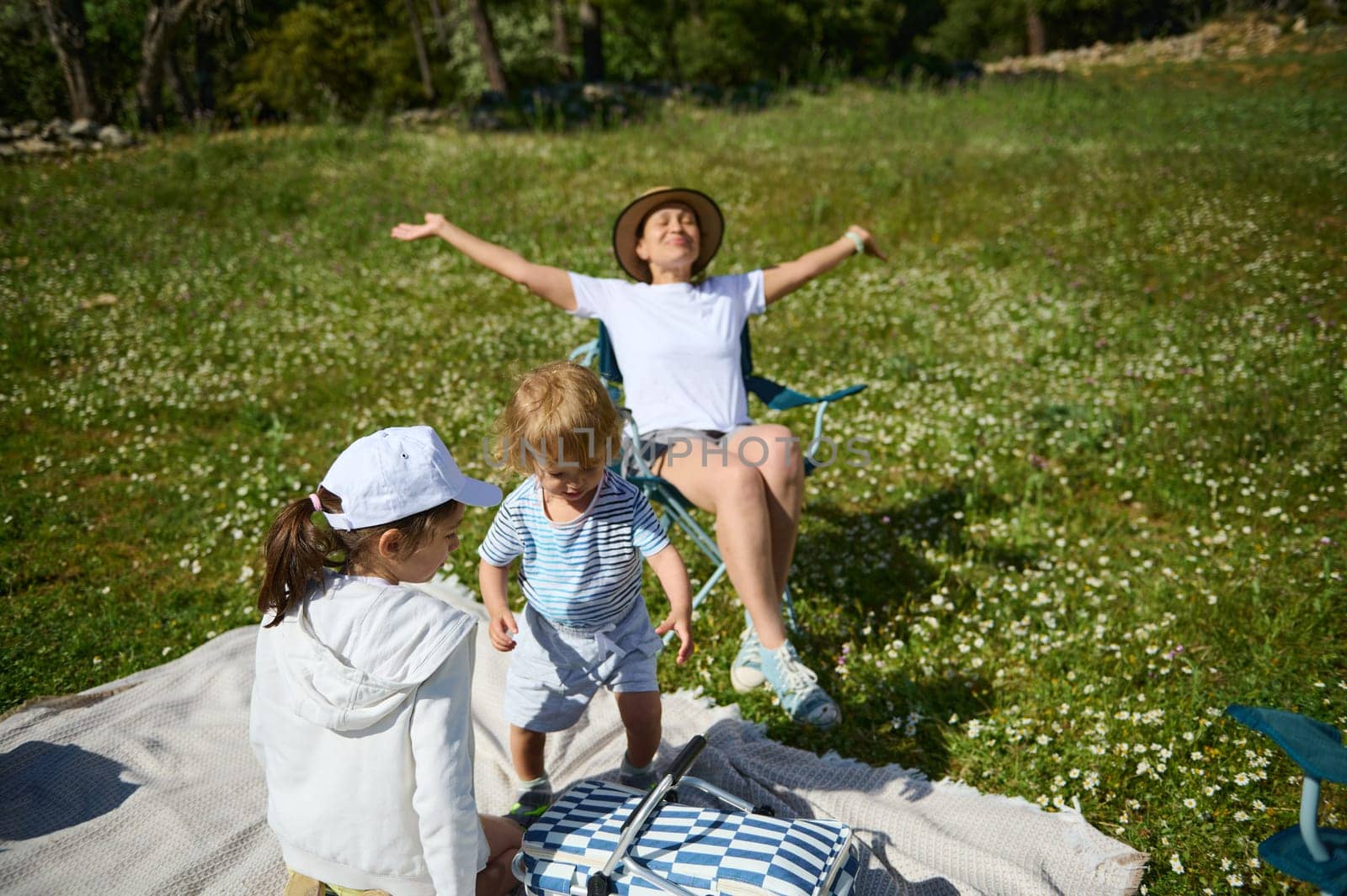A family revels in nature's beauty with a joyful picnic on a flower-dotted meadow under the radiant sunlight, enjoying quality time together.