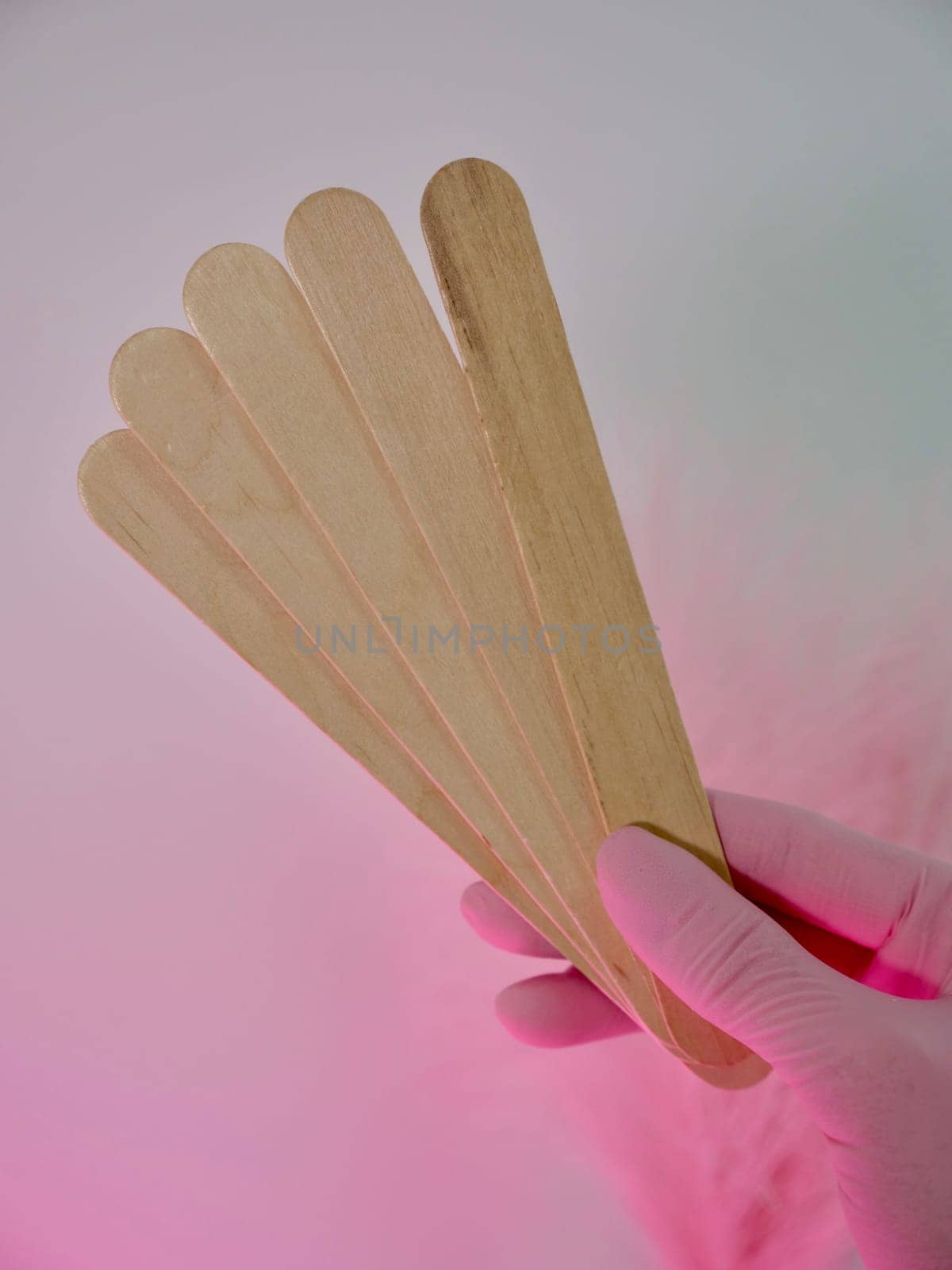 Wooden sticks for applying wax and cosmetic procedures on a pink isolated background