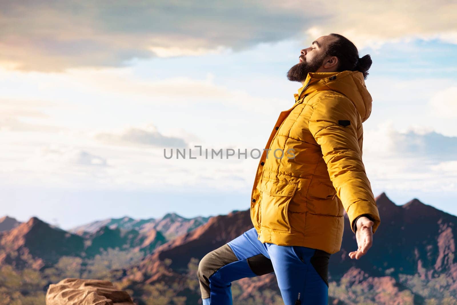 Pleased active explorer gazes at the endless sky and towering peaks, reflecting on extreme hiking activity and conquering fears. Enjoys breathtaking mountain view, nature lover.