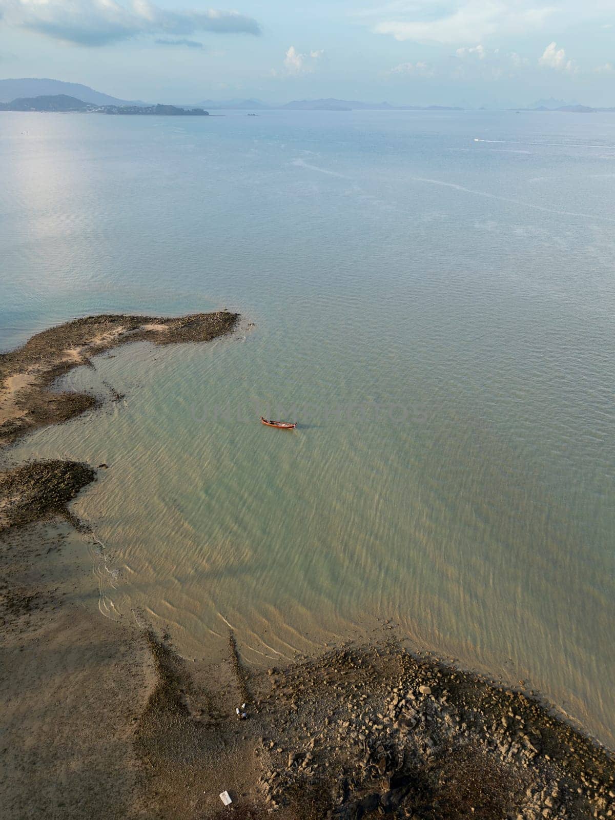 Drone shot of tropical sailboats in a turquoise bay near the harbor, boats floating in crystal clear water near a scenic Thai island with rocky beach. Picturesque shoreline with fun activities.