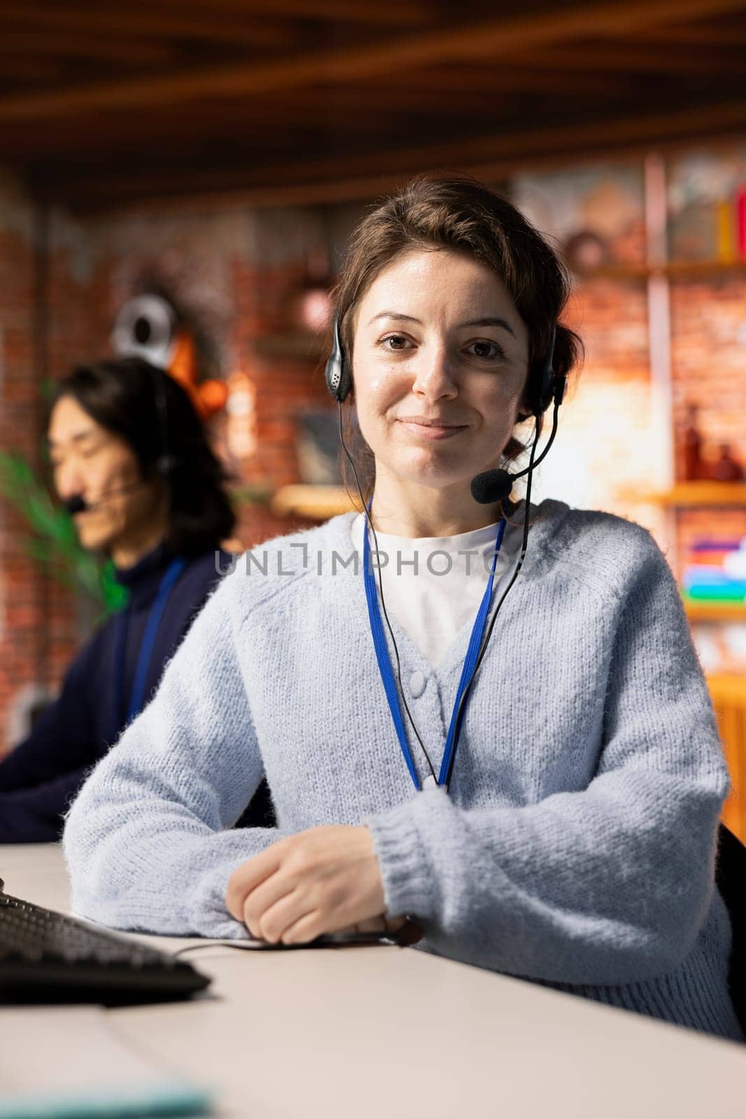 Portrait of smiling call center agent talking with customer, adhering to company provided communication guidelines. Happy customer support worker following call script during chat with client