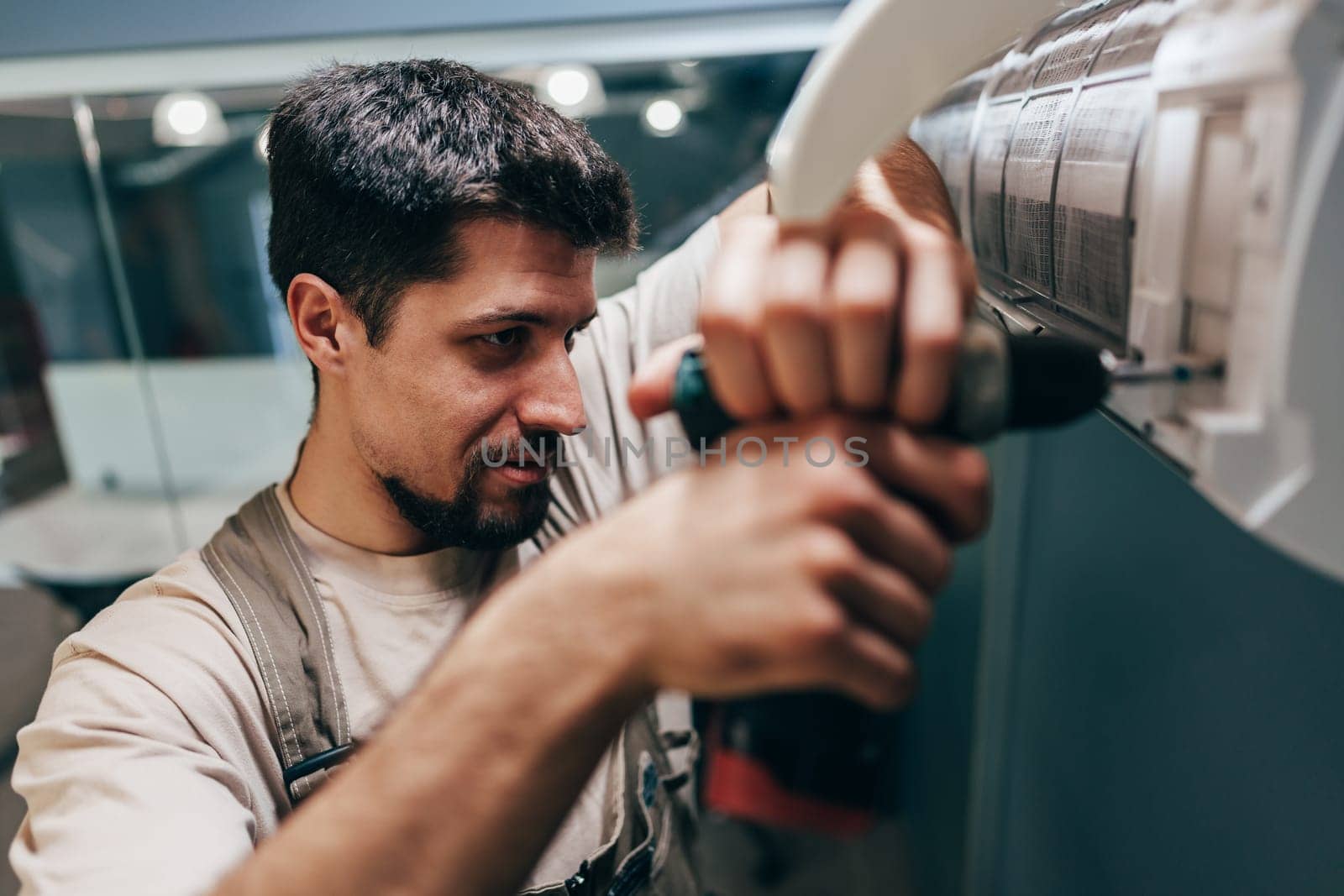 A skilled technician focuses on installing an air conditioning unit inside a home. He uses a drill, showcasing his expertise and attention to detail in the HVAC installation process.