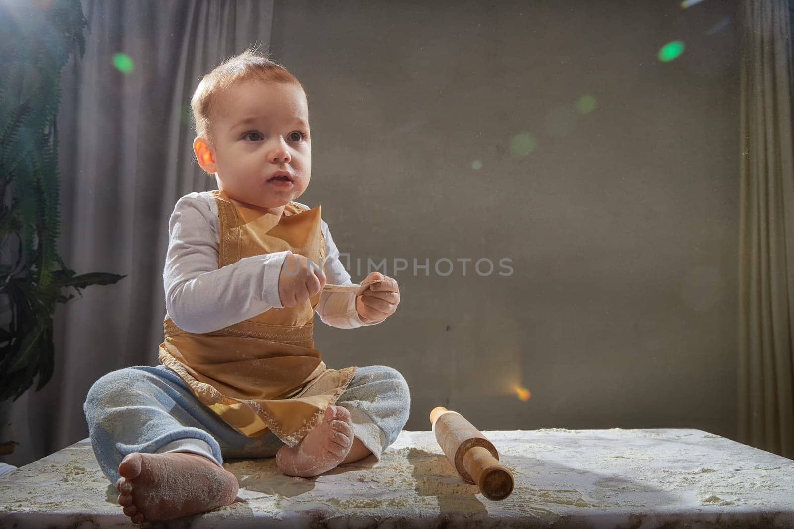 A boy explores the texture of flour while playing in a studio, showcasing a fun and creative cooking activity.