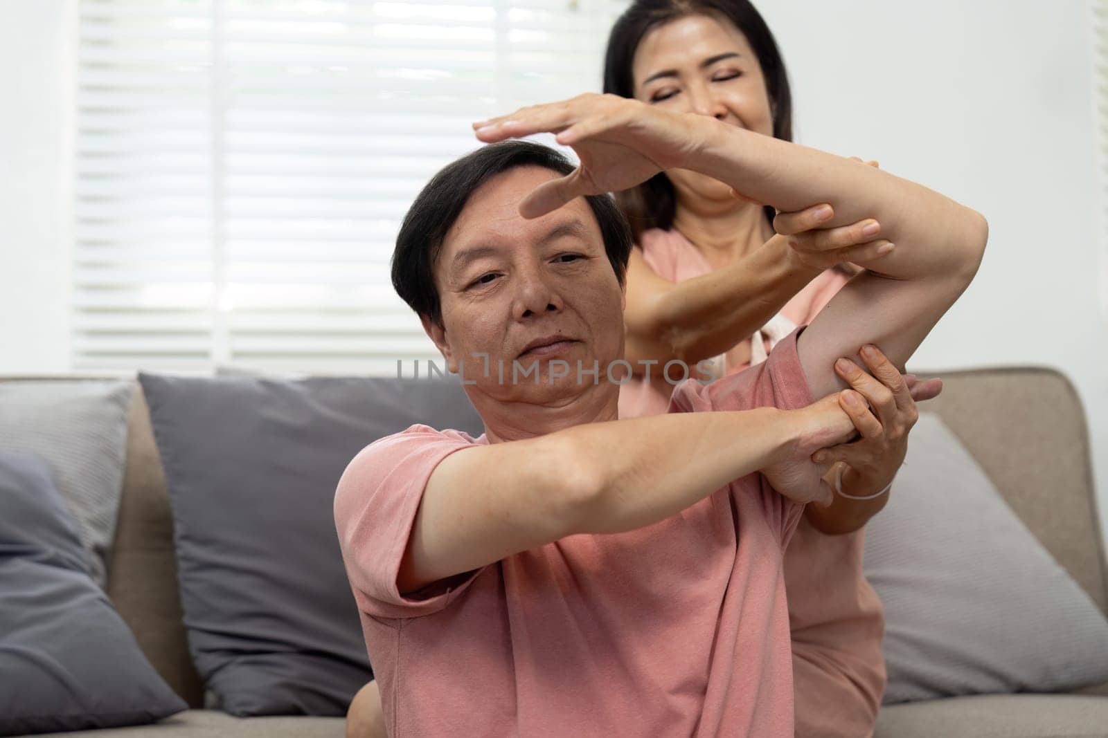 An elderly couple engages in stretching exercises, promoting wellness and care for each other's health.