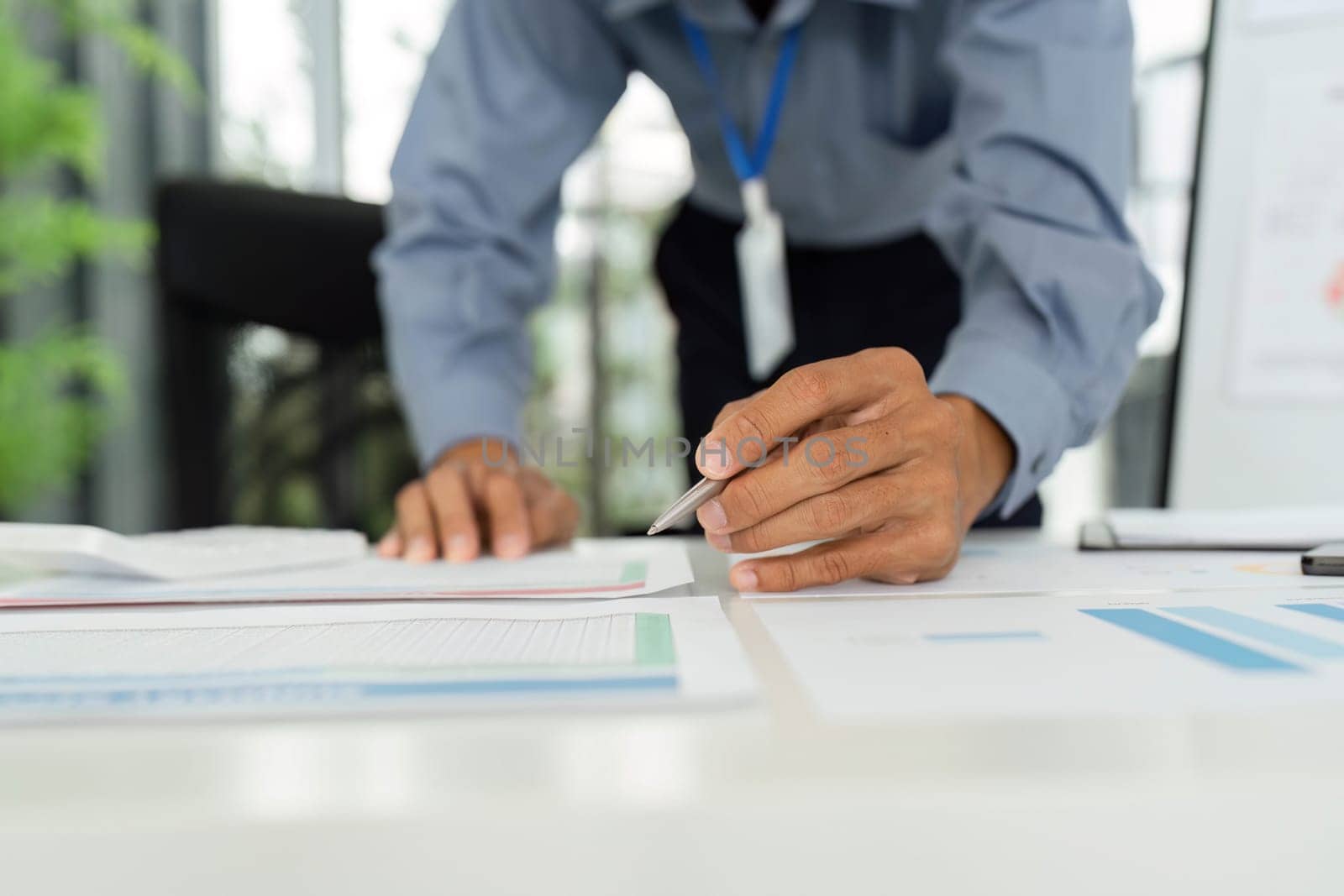 A businessman examines financial reports closely, demonstrating attention to detail and strategic planning in a modern office.
