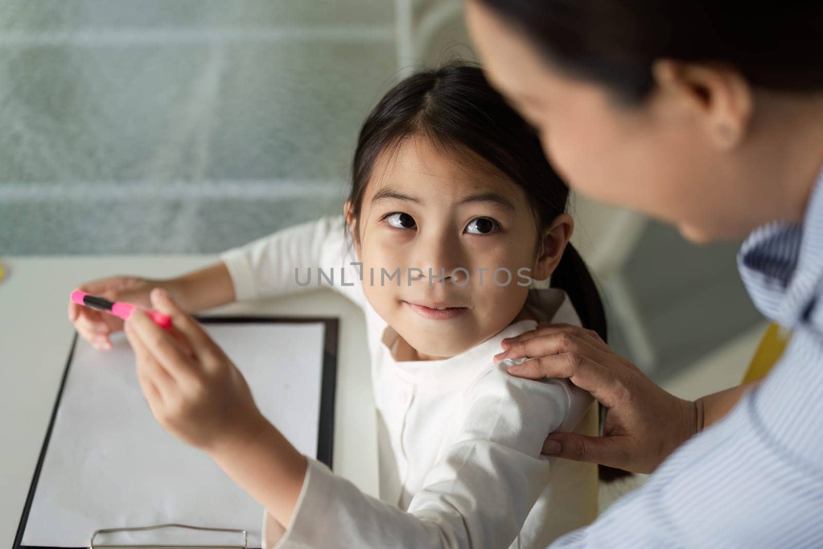 A young student concentrates on her schoolwork, showcasing a moment of focus and determination in a bright classroom.
