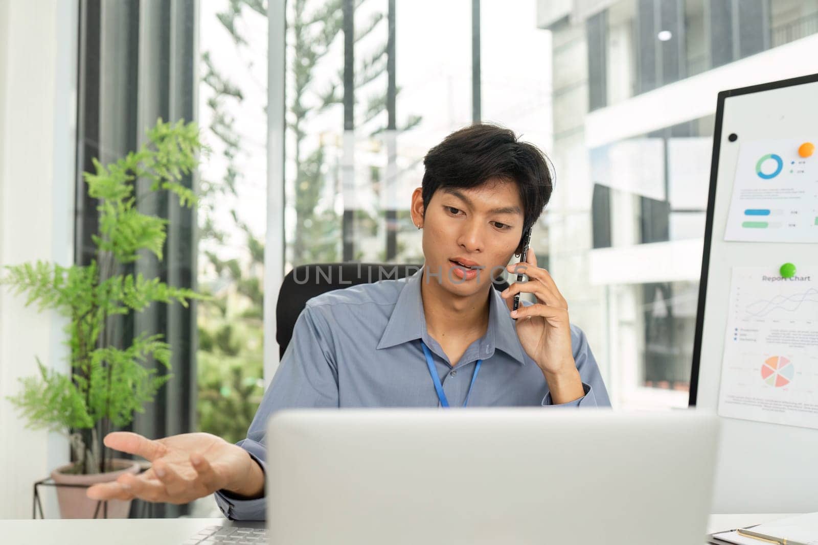 A young man animatedly discussing financial strategies on a call while reviewing data in a contemporary office environment.