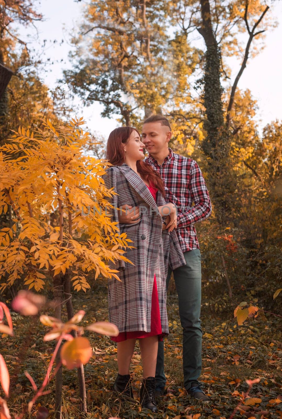 young couple in love hugging in autumn park. golden autumn around them. concept of romance, love.