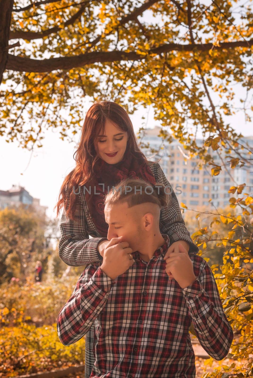 A couple in love in an autumn park, sitting on a bench, talking, laughing and holding hands. General plan. The guy kisses the girl's hand. They look at each other. Golden autumn all around.