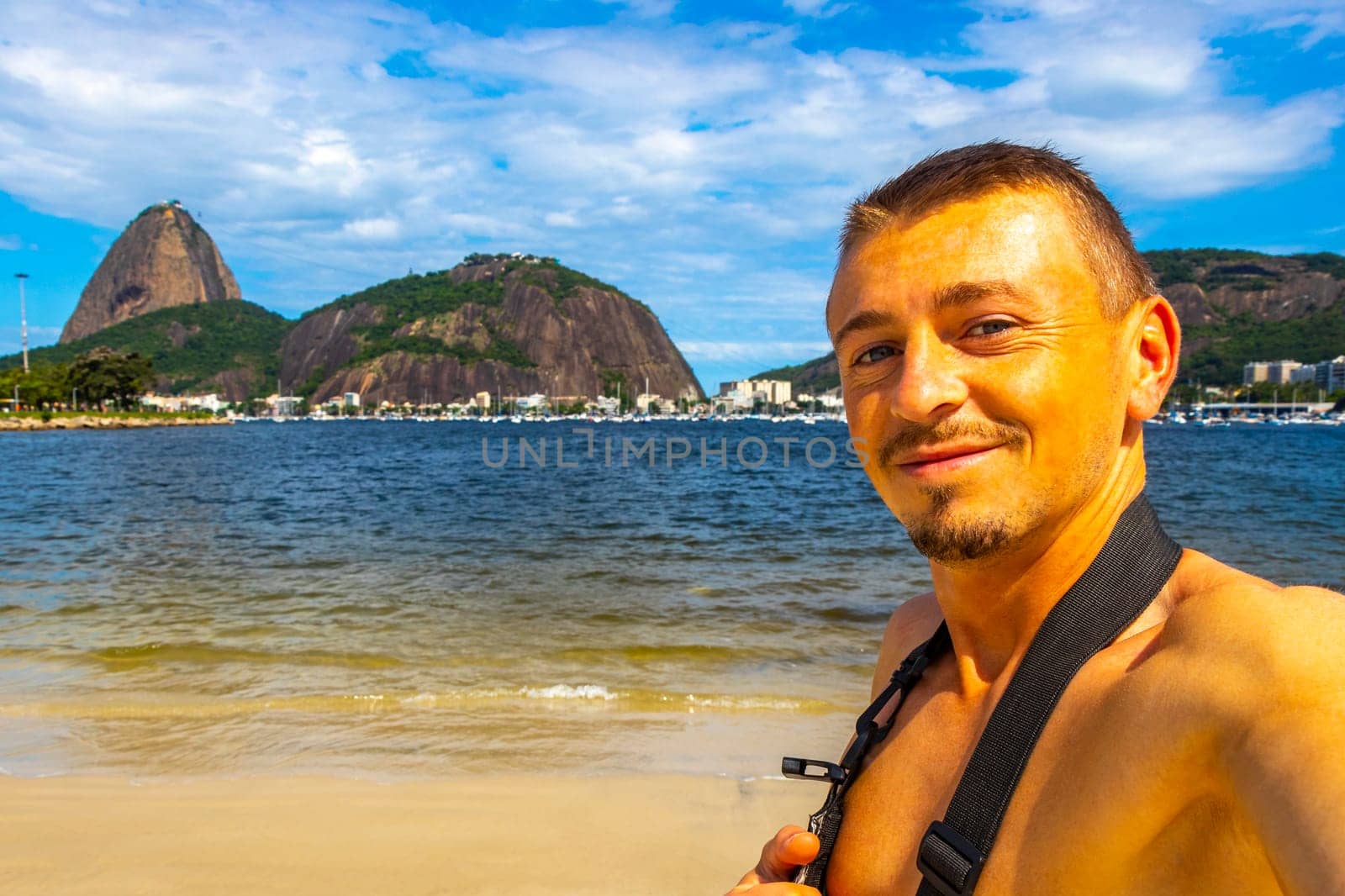 Handsome Tourist Traveler Man is Posing at the Sugarloaf Sugar Loaf Mountain Hill Rock Pao de Acucar Panorama View in the Urca Village of Rio de Janeiro Brazil.