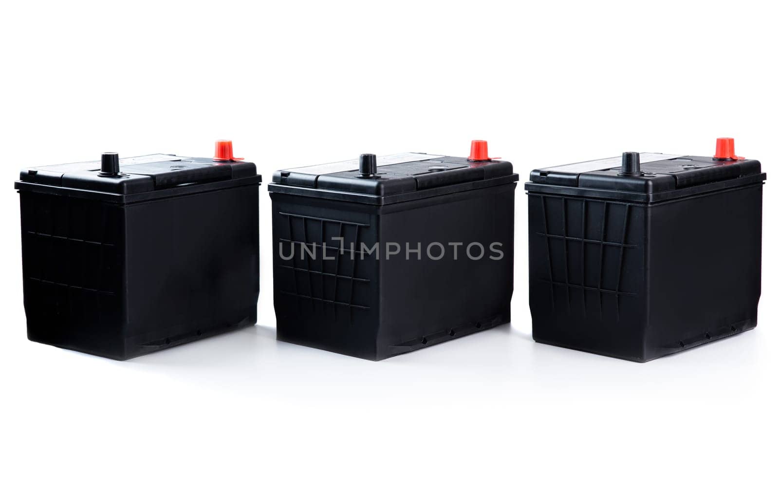 Three identical black car batteries in a row on white background. Isolated automotive parts for passenger vehicle repair, catalog, or store use.
