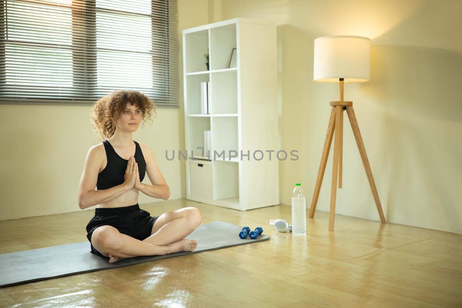 Peaceful young woman practices meditation in a bright home.