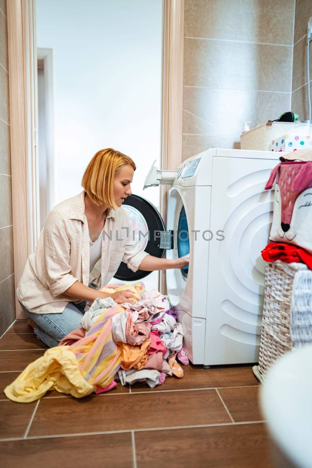 A woman organizes laundry in a cozy laundry room.