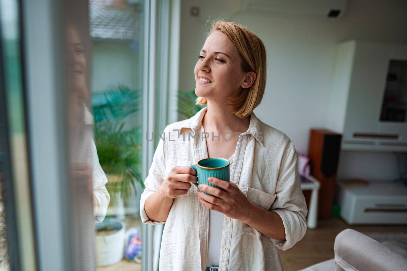 Woman savors a peaceful moment with tea by the window