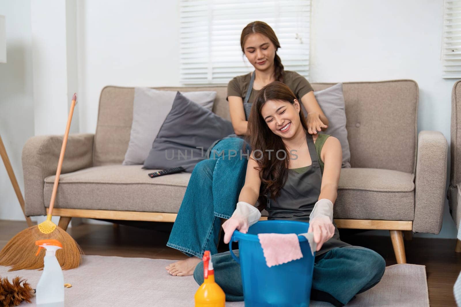 In a light-hearted cleaning session, one woman helps another while they clean, creating a positive and enjoyable atmosphere in their living room.