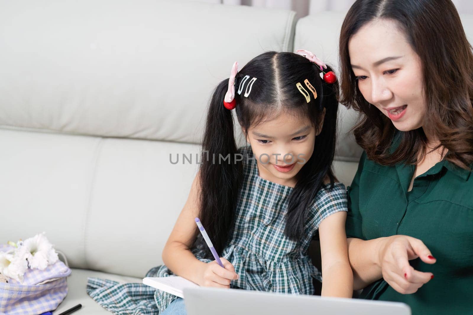 A mother helps her daughter navigate online learning, emphasizing the importance of technology in education as they prepare for school.