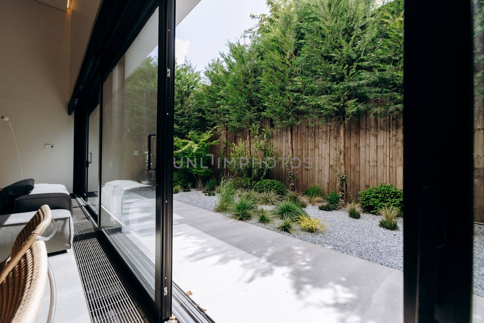 In a cozy living room, there are beautiful sliding glass doors that provide access to a lush garden outside, creating a seamless connection with nature