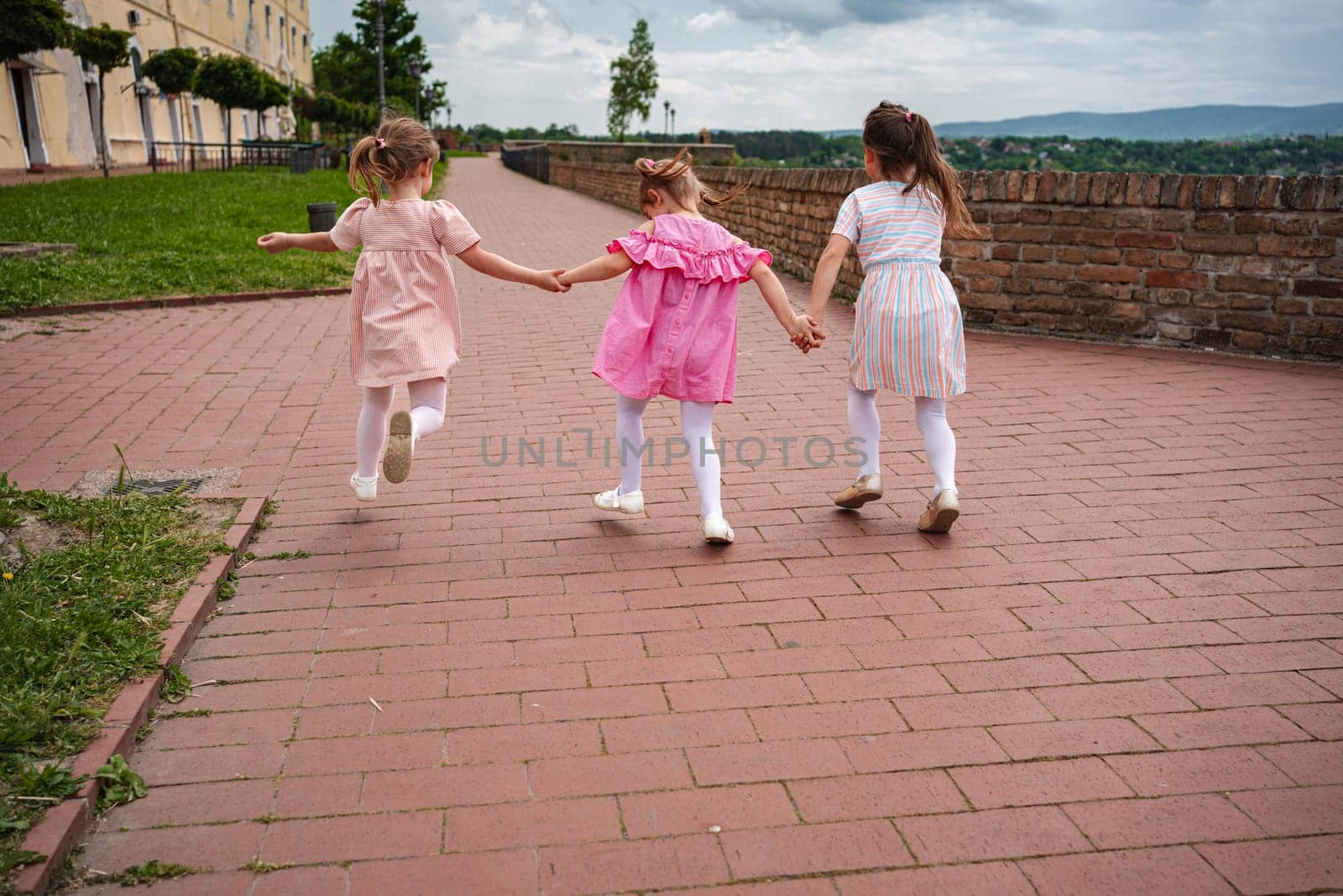 Three little girls holding hands as they run through history.