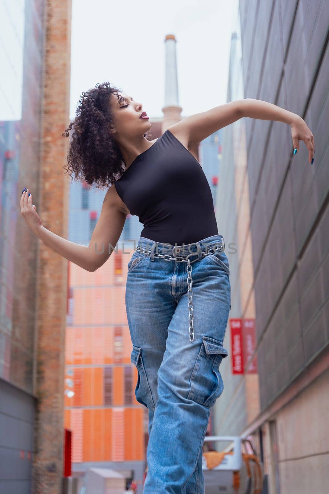 African American woman dancing in a creative pose between benches in an urban setting. he wears casual clothes and shows balance,strength, and expression. Concept of movement, art,and freedom.Vertical