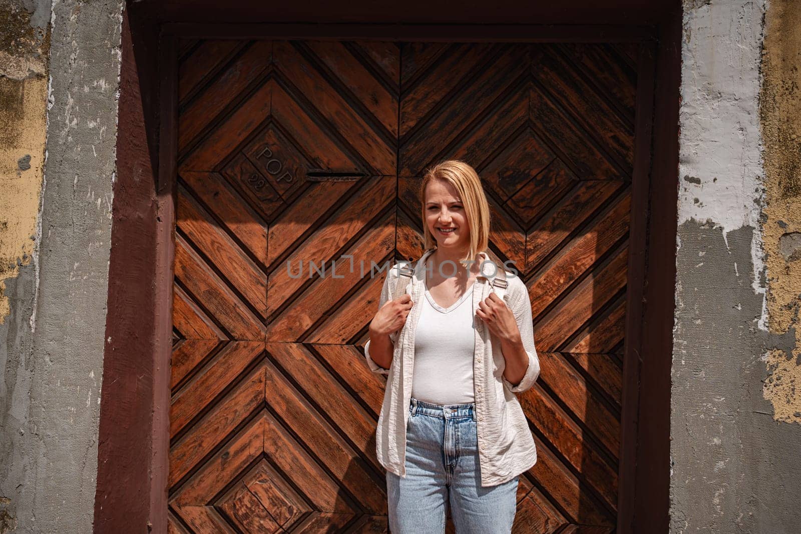 Young traveler poses cheerfully by ancient fortress door.