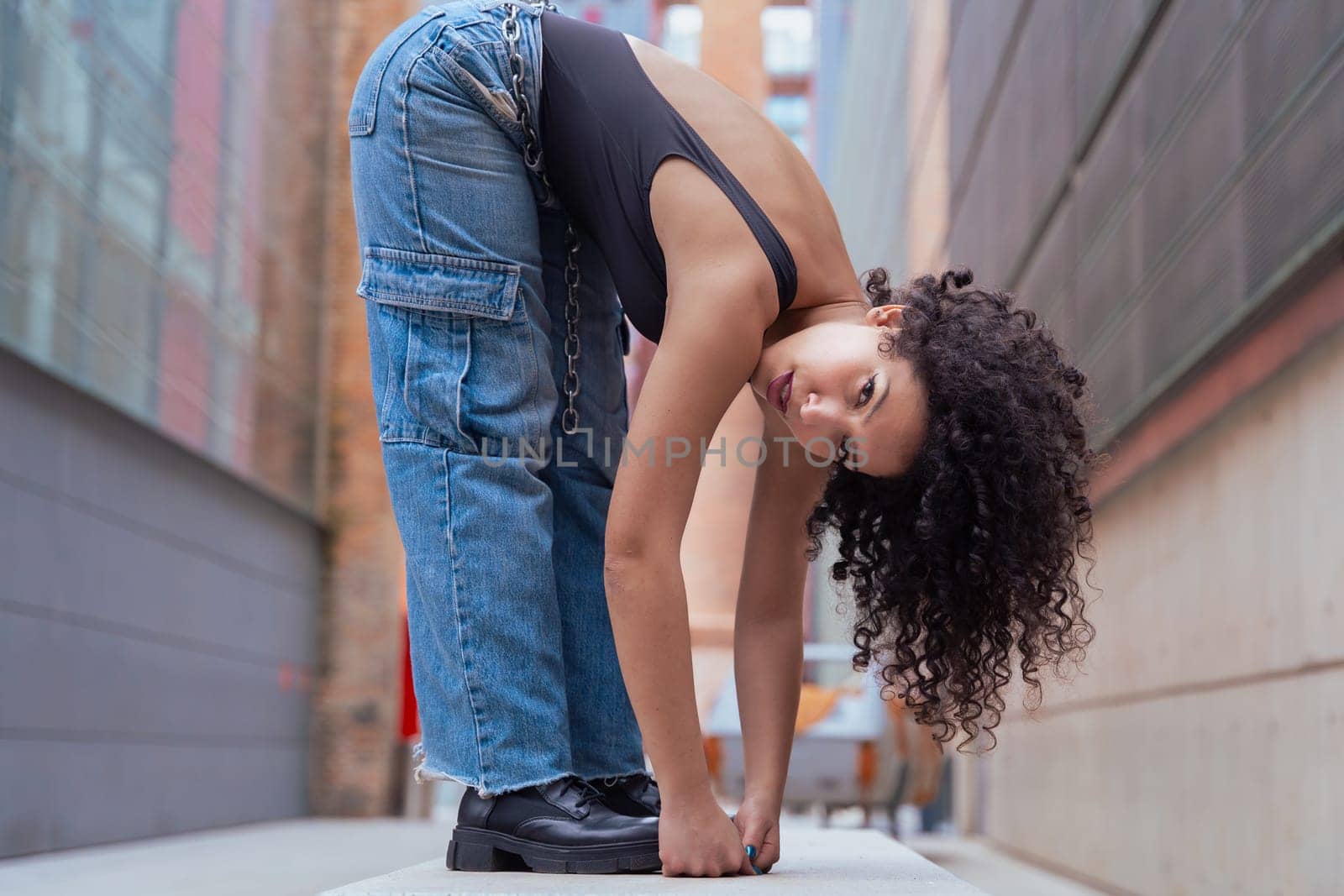 African American woman dancing in a creative pose between benches in an urban setting. he wears casual clothes and shows balance,strength, and expression. Concept of movement, art,and freedom