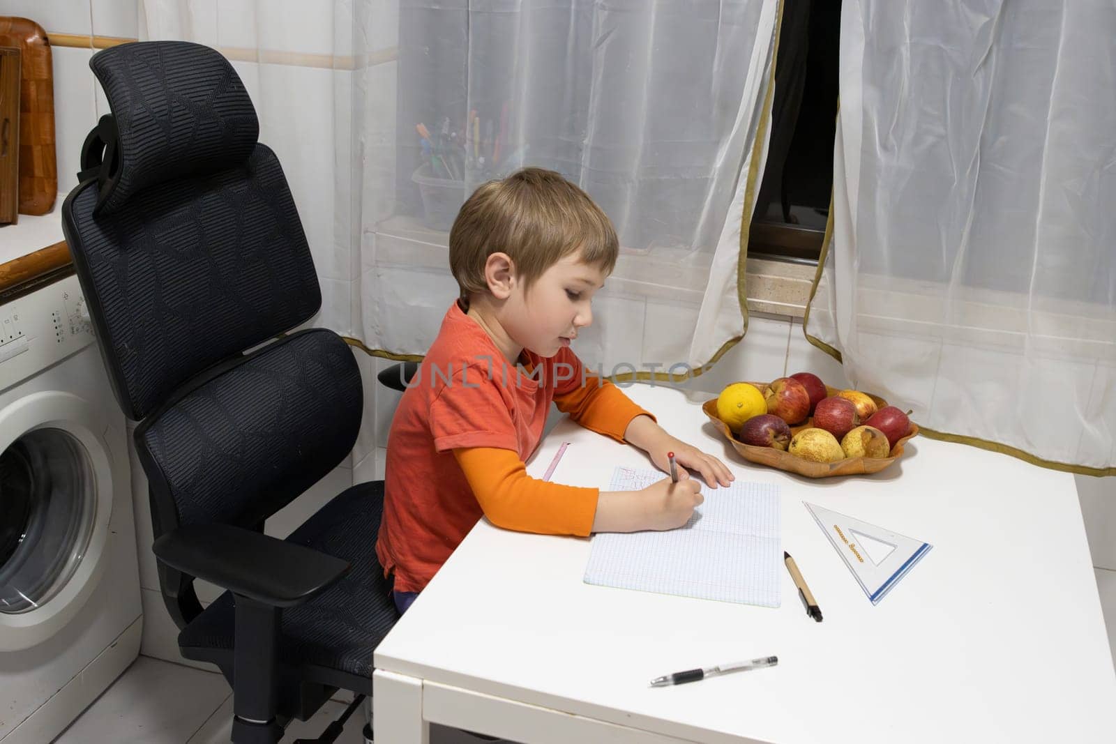 Child writing on notebook sitting on an ergonomic chair at home