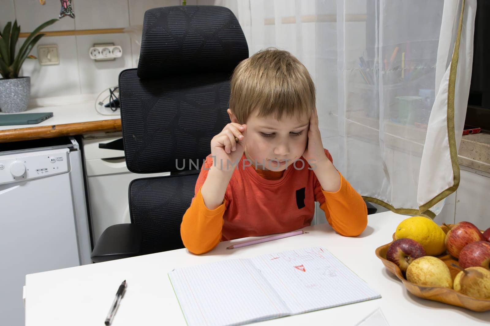 Preschool child concentrating on his homework while sitting at the kitchen table