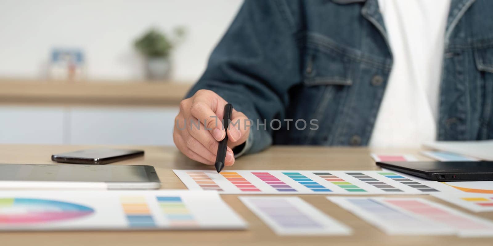 A designer selecting colors from a palette while using a digital pen on a tablet, showcasing creativity in a modern workspace.