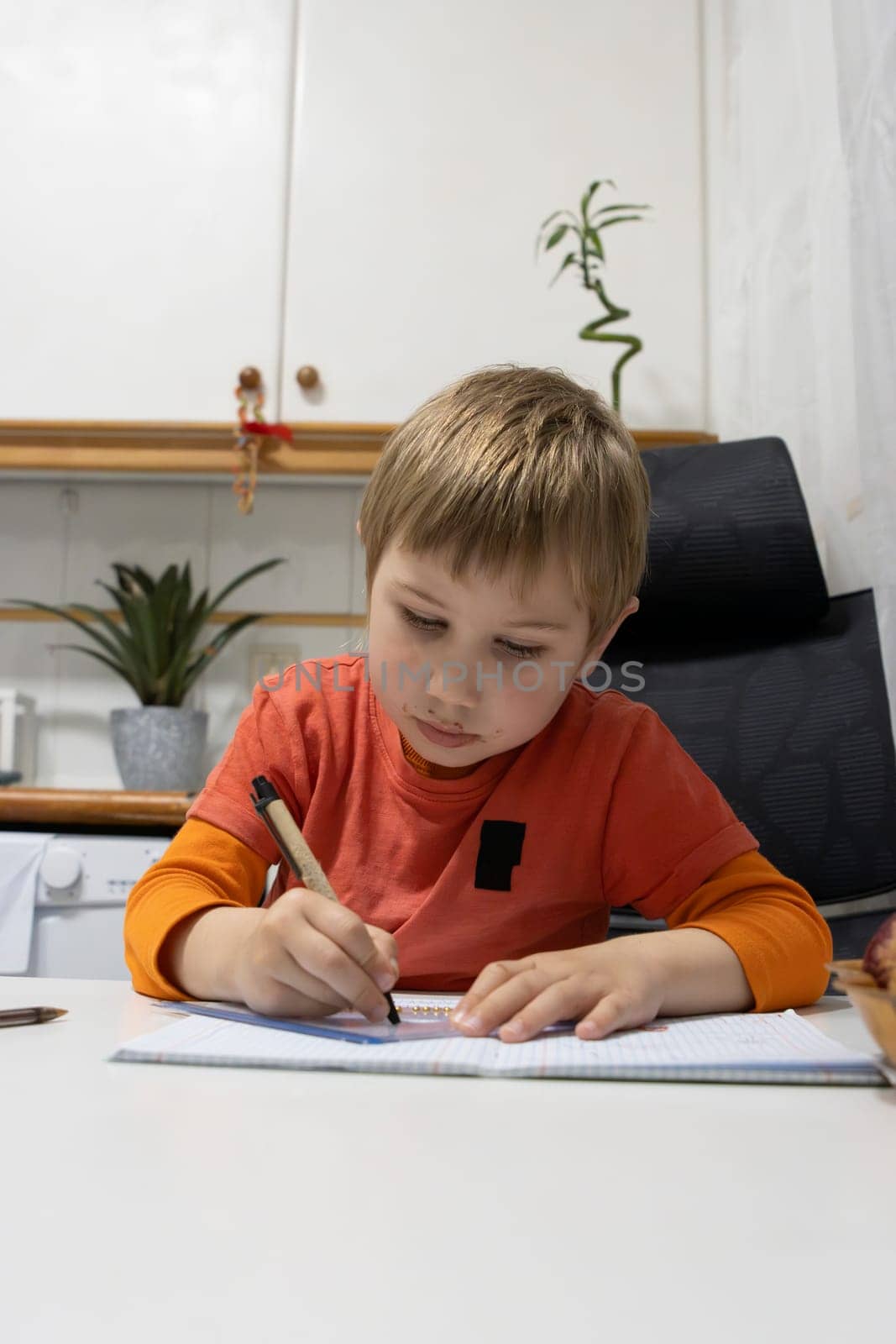 Young student doing homework and writing on notebook at home