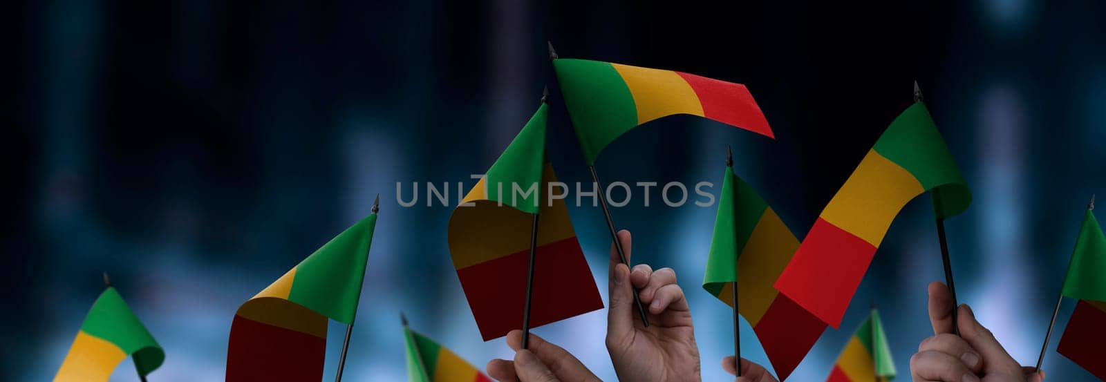 Mali flags in their hands on a blurred urban background. The photo illustration was created without the use of artificial intelligence, only using Photoshop.