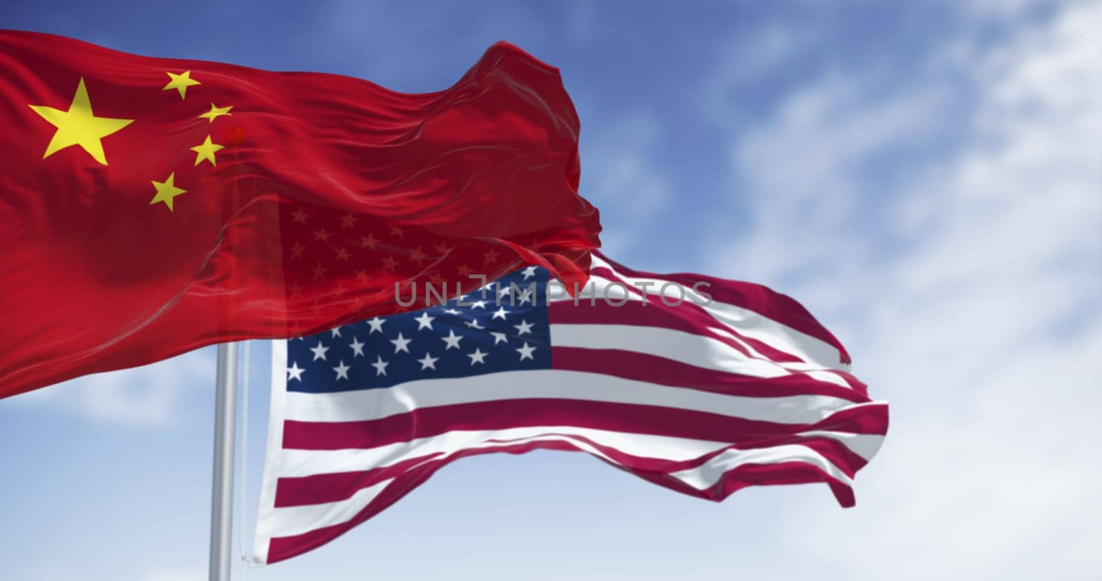 3D render of Chinese and American flags waving side by side in the wind, symbolizing diplomacy, patriotism and international relations under a clear sky.