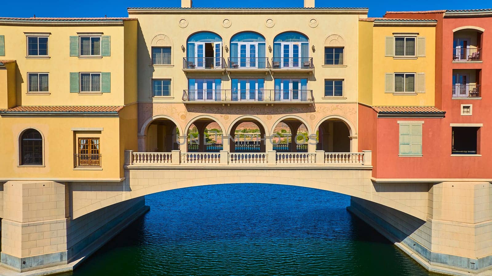 Elegant Mediterranean-style bridge connects colorful buildings over a serene canal at Lake Las Vegas in Nevada, USA, capturing luxury waterfront living and European-inspired architectural beauty.