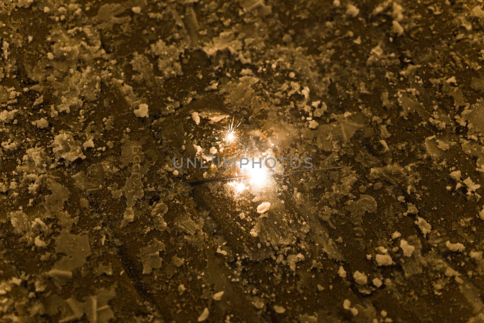 Sparkler burns on winter pavement. Concept of celebration, magic, fleeting moment in urban setting.