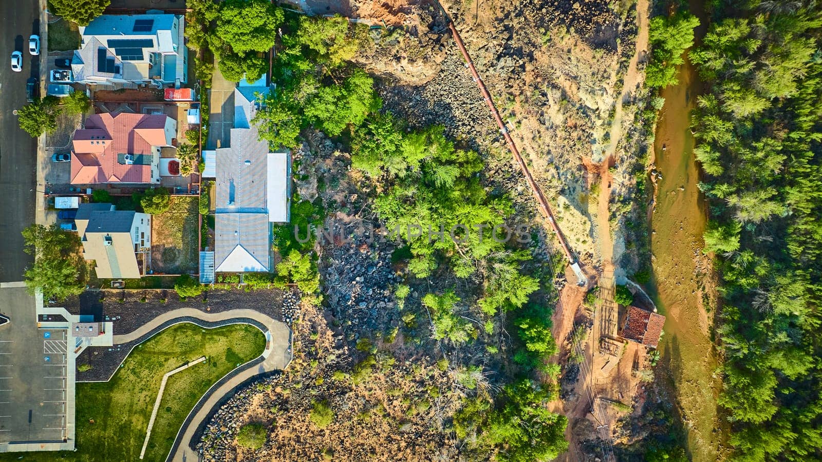 Aerial view of a suburban neighborhood in Utah bordering rugged wilderness and the winding Virgin River. Showcasing the contrast between human development and untouched natural landscape.