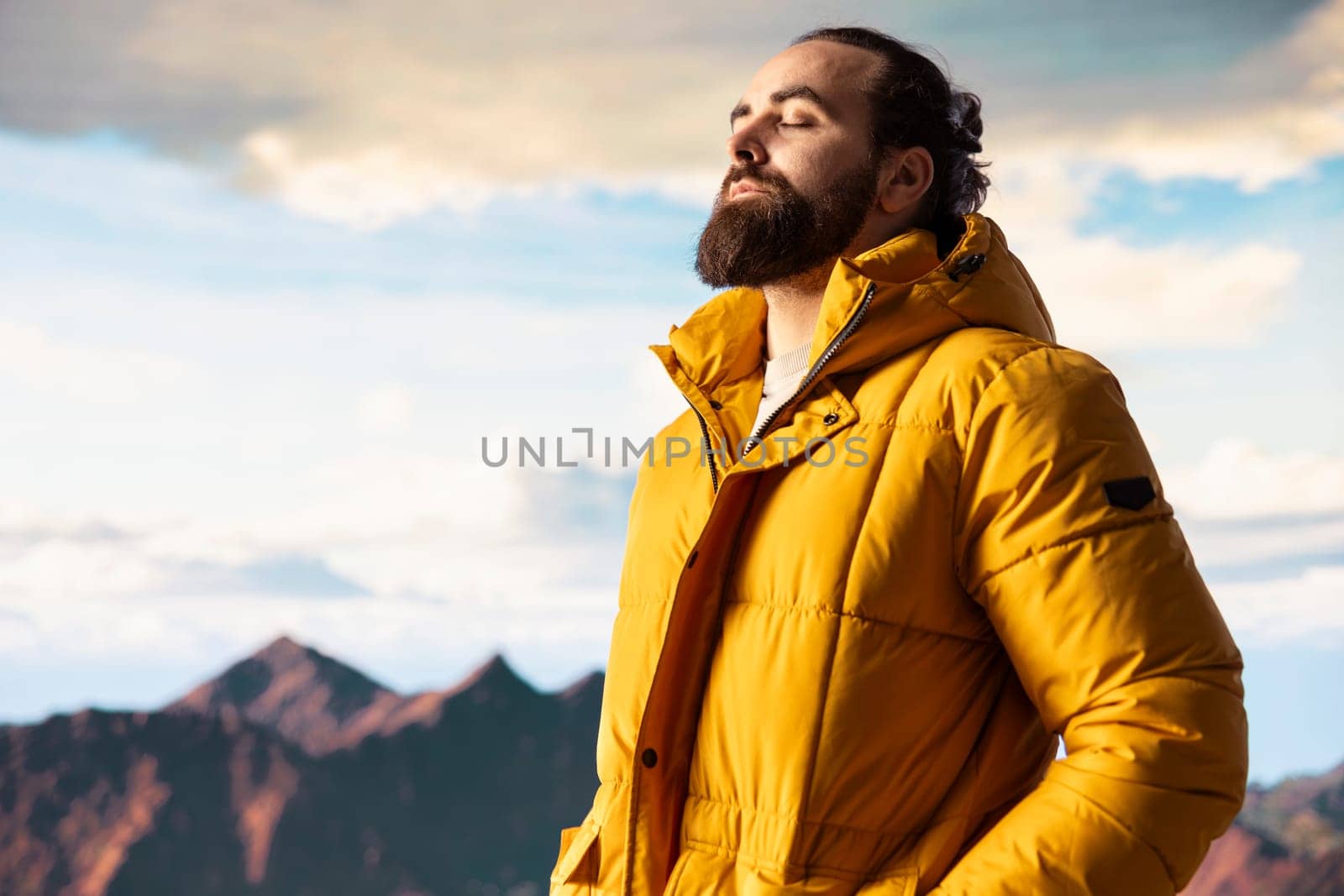 Explorer on a mountain peak taking in the fresh air and panoramic scenery. Climber nature lover admires the stunning landscape of rugged peaks and vast sky, adventure and sightseeing.