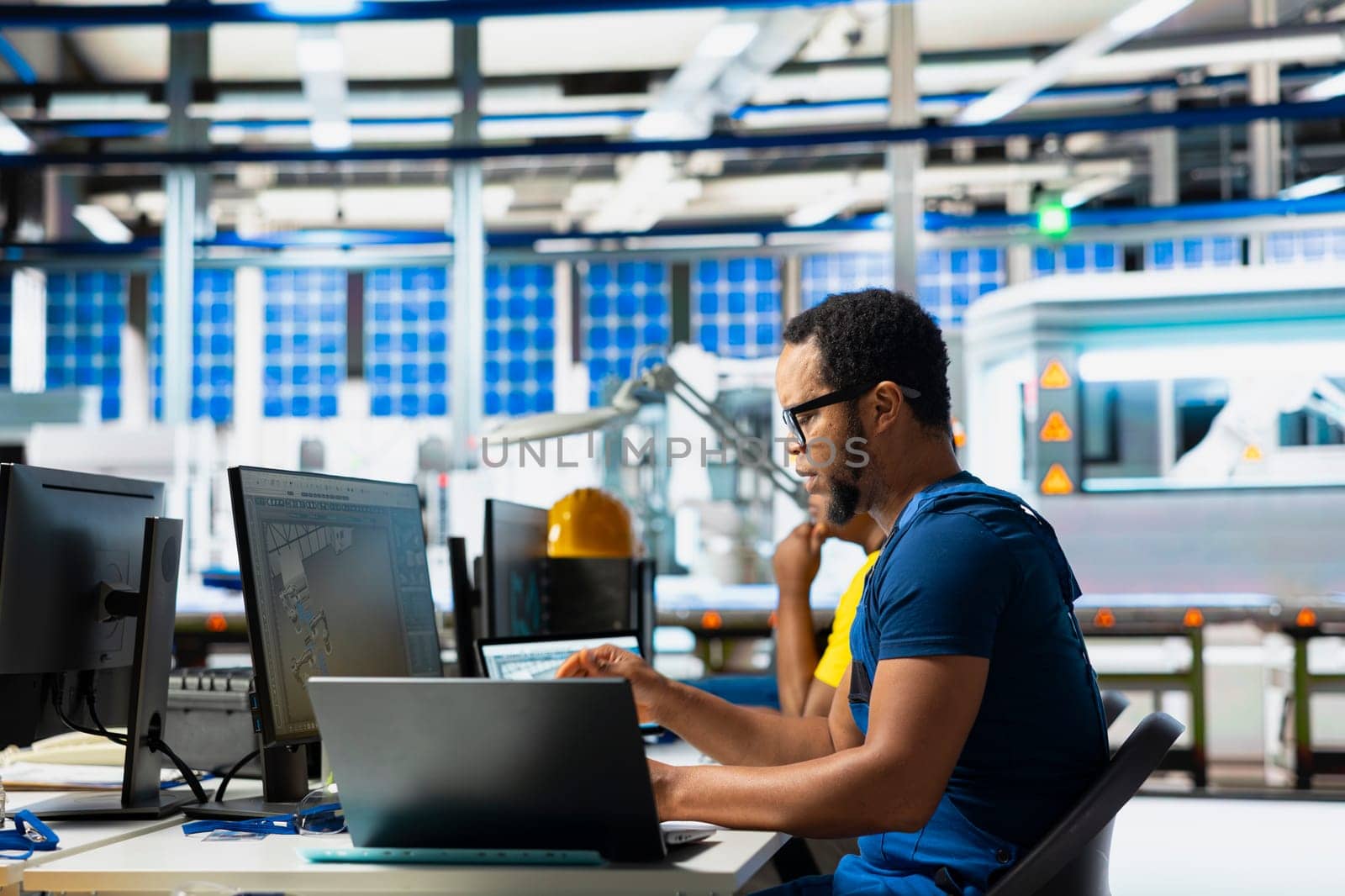 Black engineer testing solar technology at pc setup in renewable energy facility, focusing on software troubleshooting and performance metrics. Supports eco friendly sustainable operations.