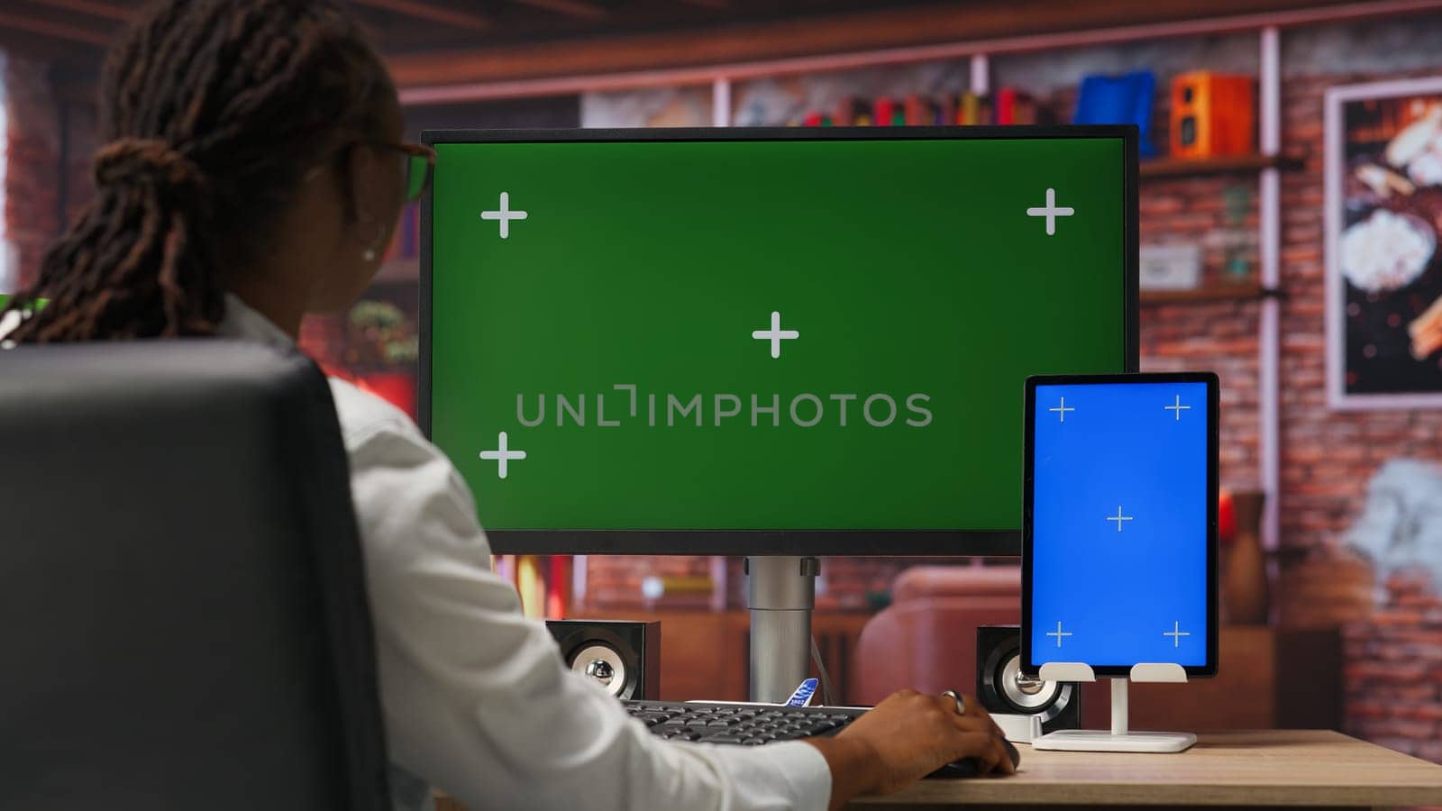 Freelancer in home office using green screen PC and mockup tablet to work on job tasks. Teleworker using chroma key computer monitor and isolated screen device to do job online